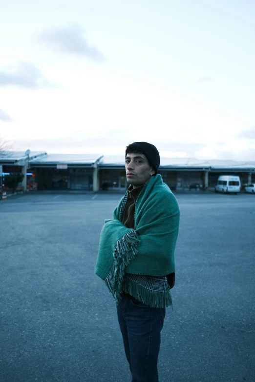 a man in green jacket and scarf posing