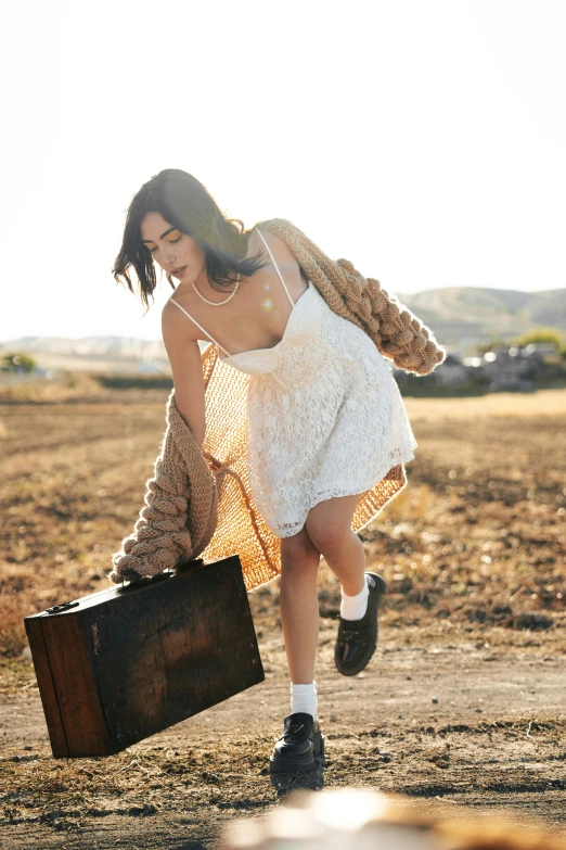 a woman dressed in white running while holding a suitcase