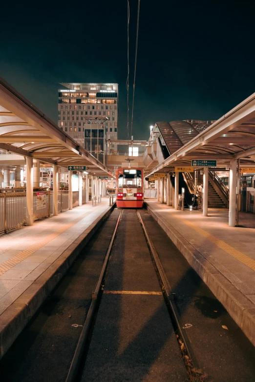 a red bus parked on the train tracks near some buildings