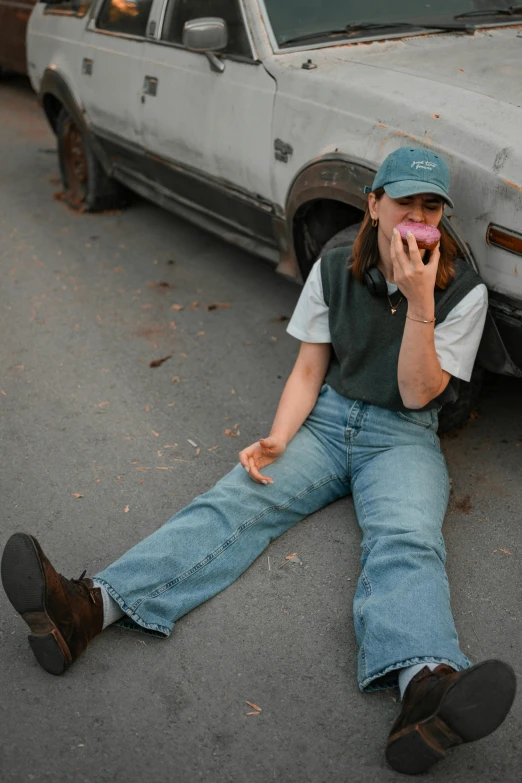 there is a person sitting by a car eating soing