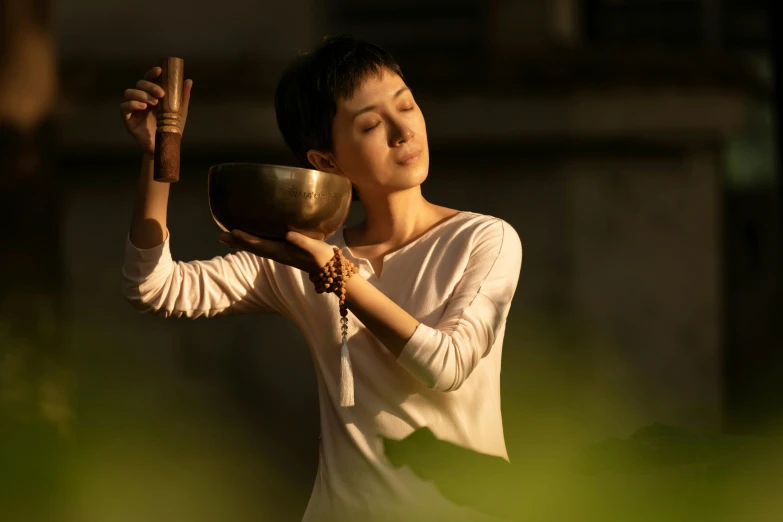 a woman holding a gold bowl and praying