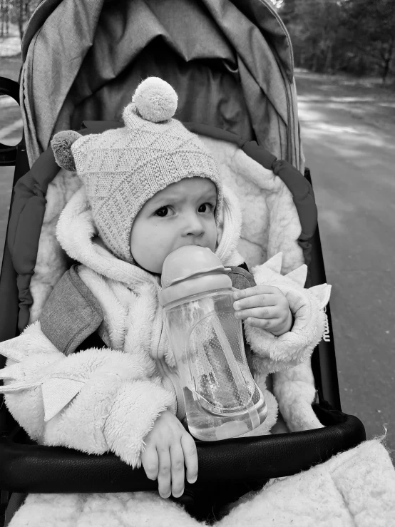 small baby is sitting in a stroller holding soing