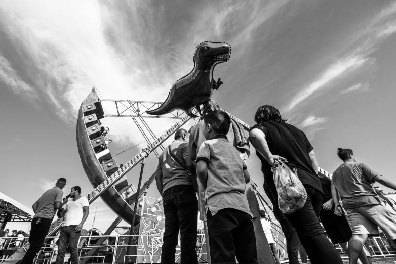 people walking towards a large replica dinosaur