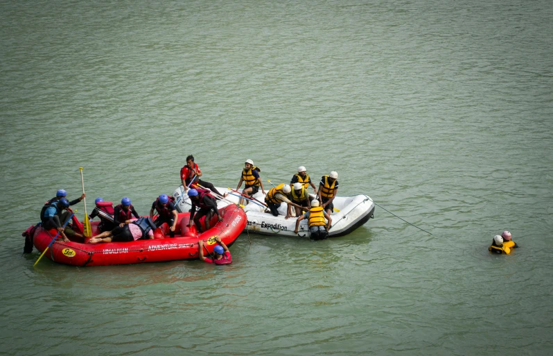 three people in rafts are on the water with life guards