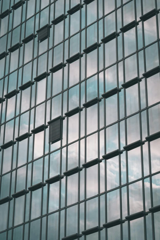 a glass facade with windows and cloudy sky