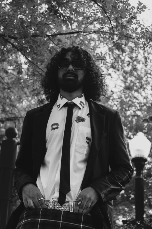 man in kilt standing in front of a tree wearing a suit