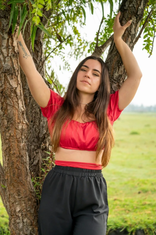 a woman leaning on a tree posing for a po