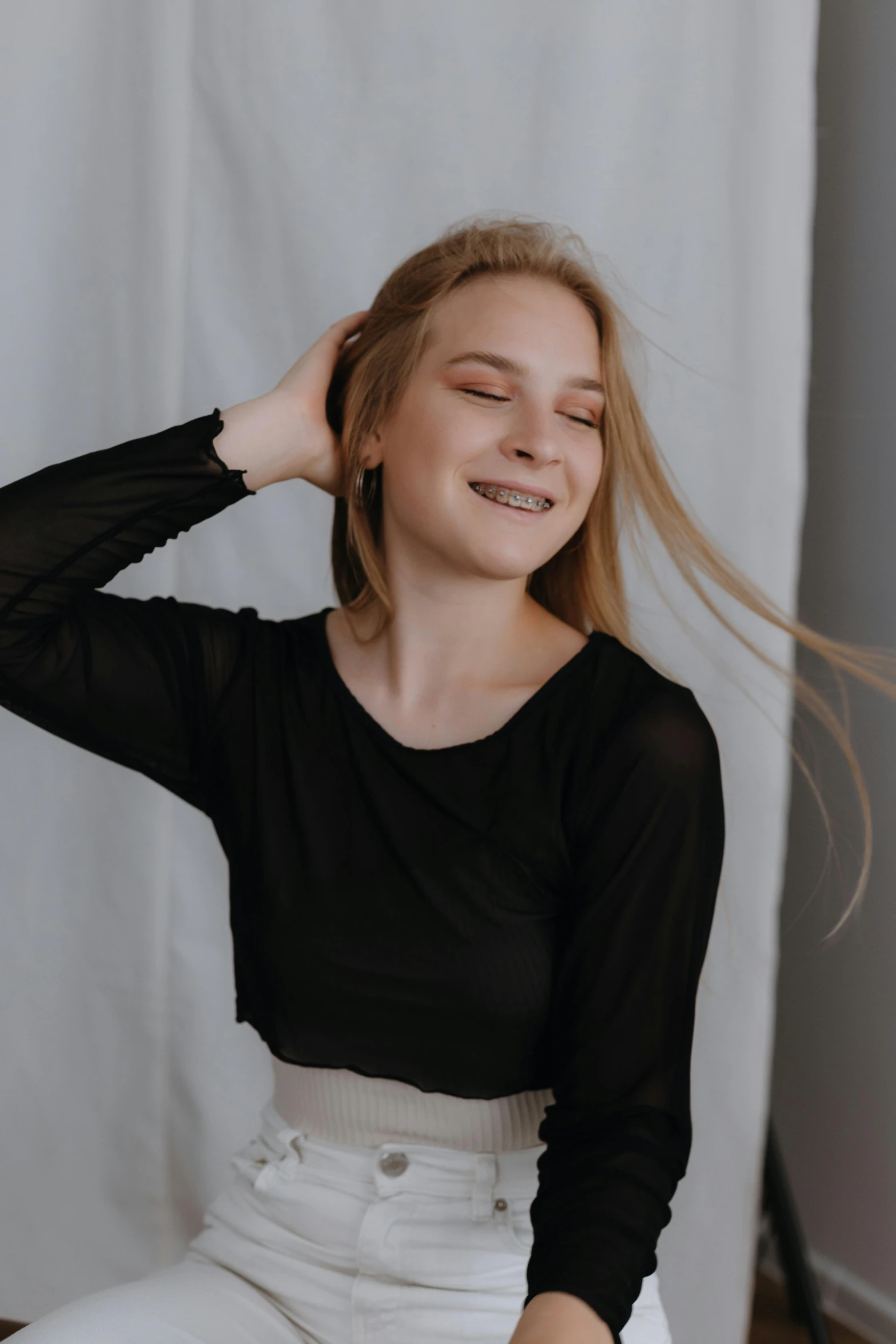 a woman in a black shirt and white pants smiles