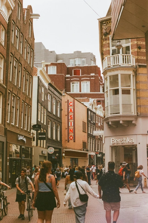 a busy sidewalk with people walking and buildings