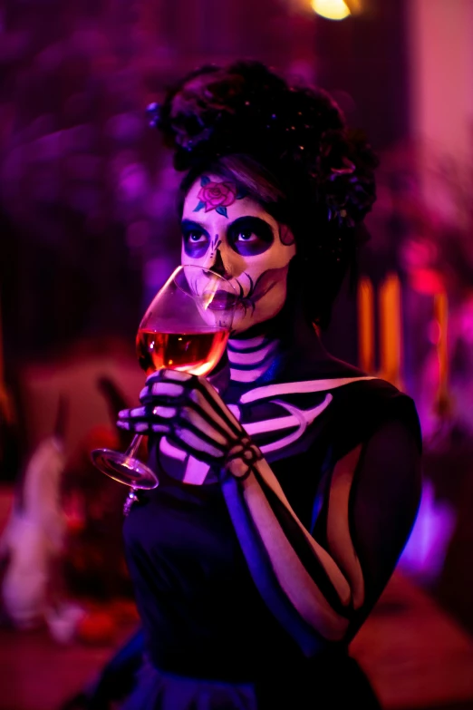 a girl in skeleton make up and makeup holds a glass of wine