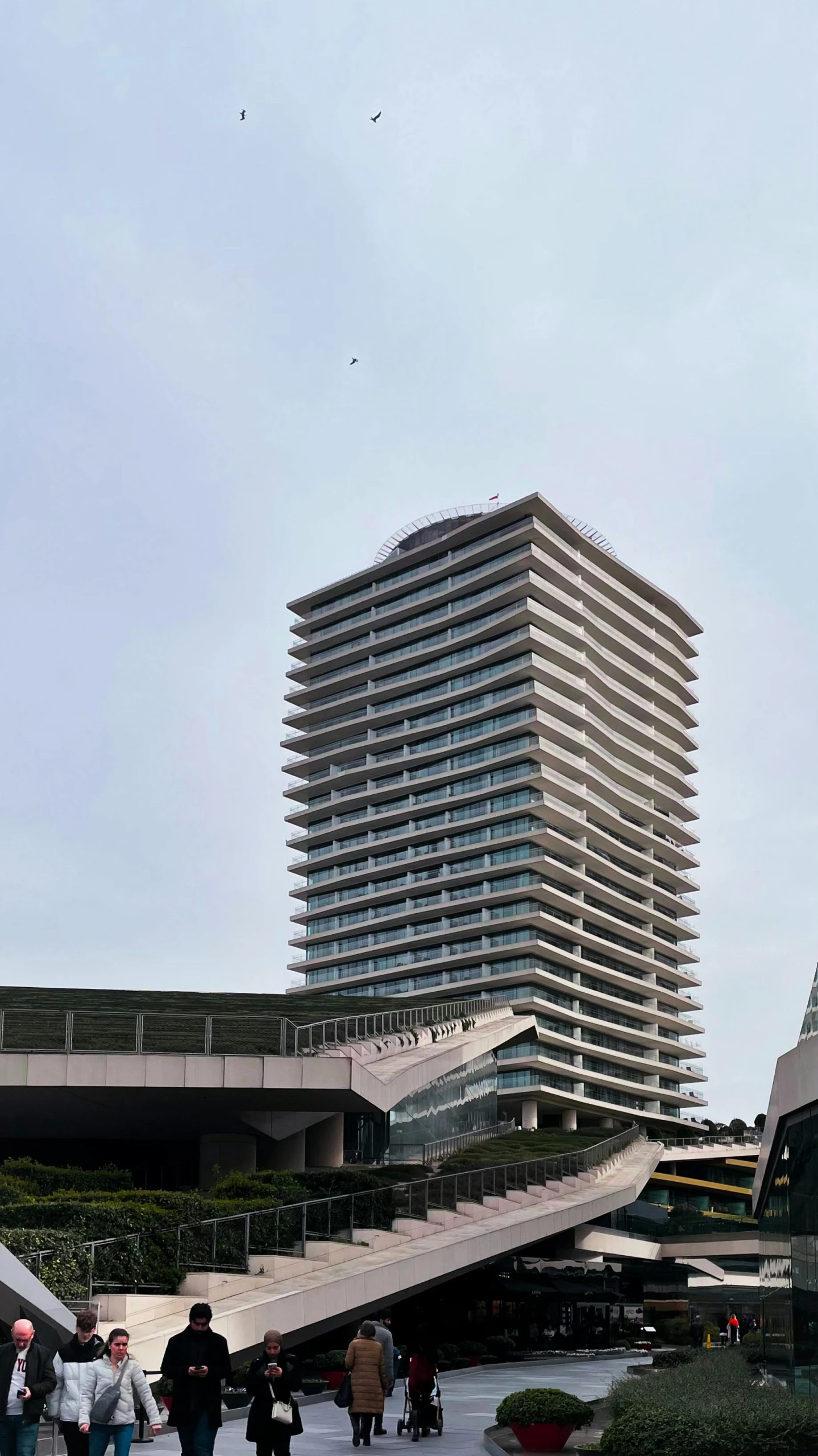 people walk on the walkway at a building with many floors