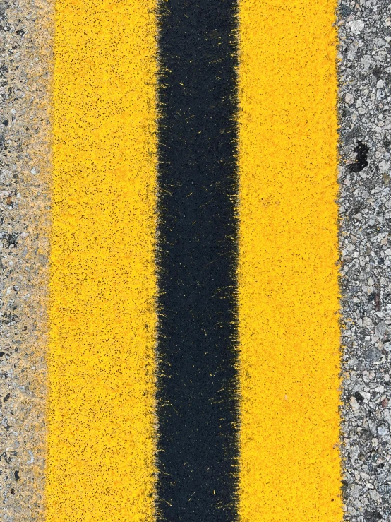 a yellow and black stripe on an asphalt surface