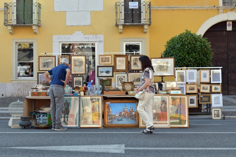 an older man looking at pictures and posters displayed in front of a building