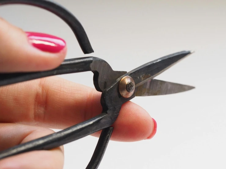 the woman is holding the black scissors and her finger is holding it
