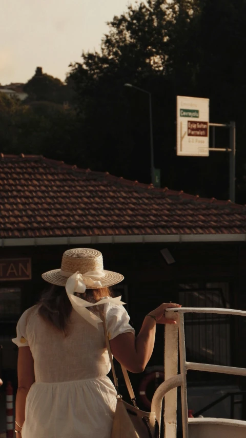 woman in white dress and hat with handbag on stairs