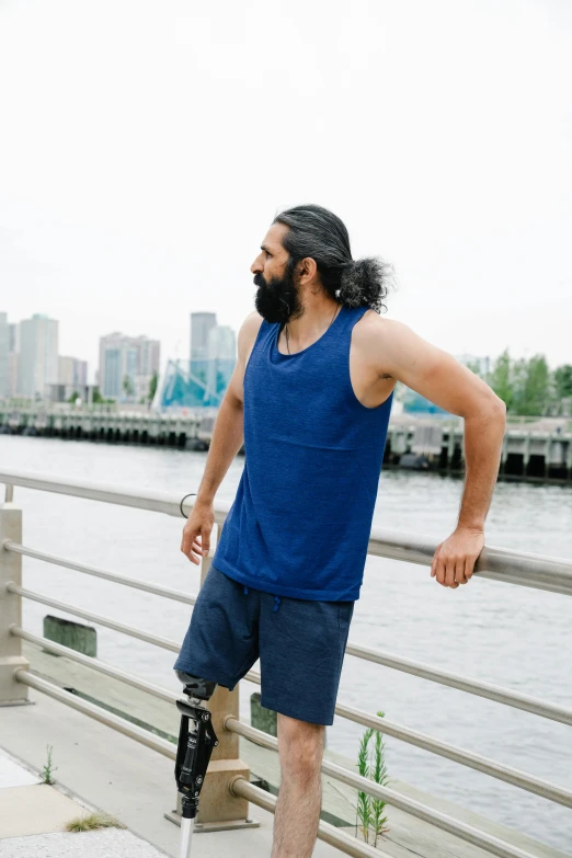 a man wearing a cast and a leg ce standing on a bridge next to the water