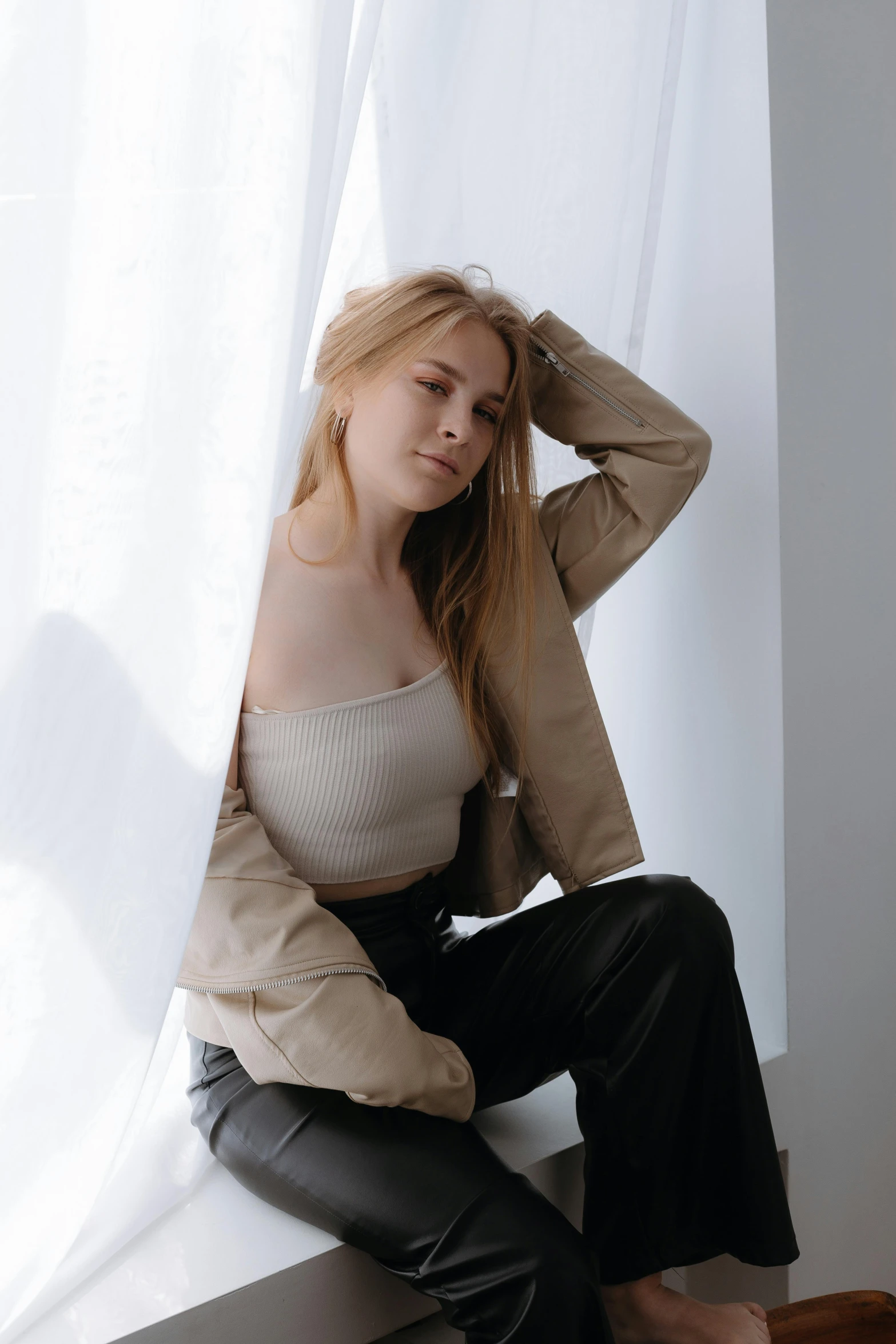 a woman wearing leather pants sitting on a ledge