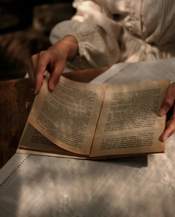 a woman in white is holding an old book