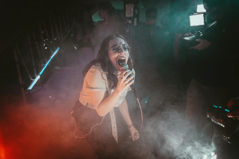 the woman stands in front of an empty stage with a microphone