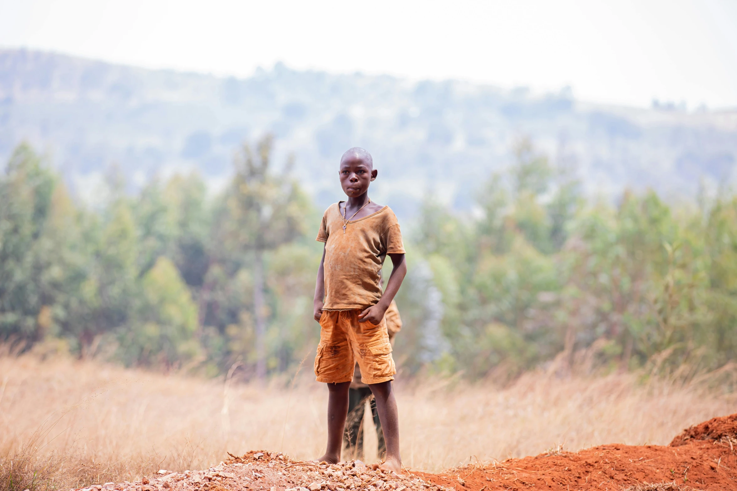 a man is standing in a field near some bushes