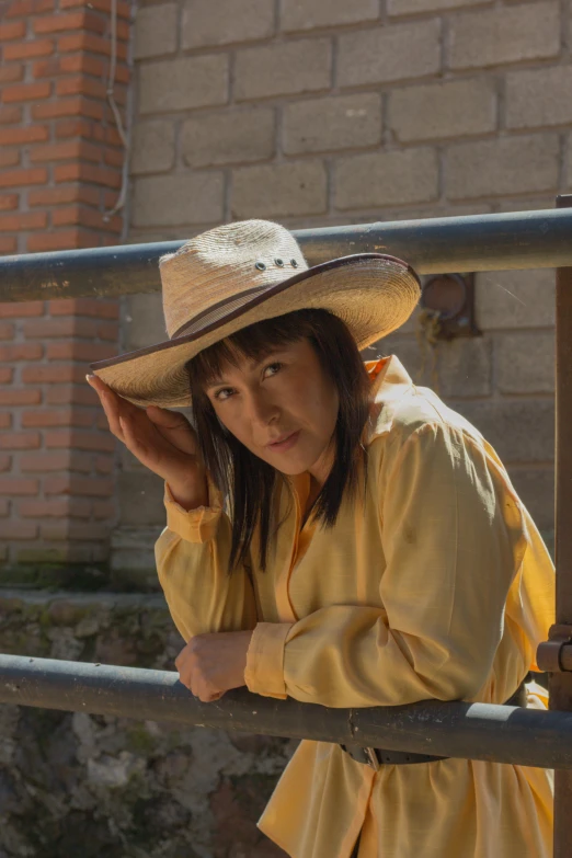 a  wearing a hat next to a metal railing