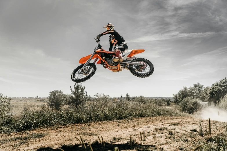 a person riding on the back of a dirt bike over a ditch