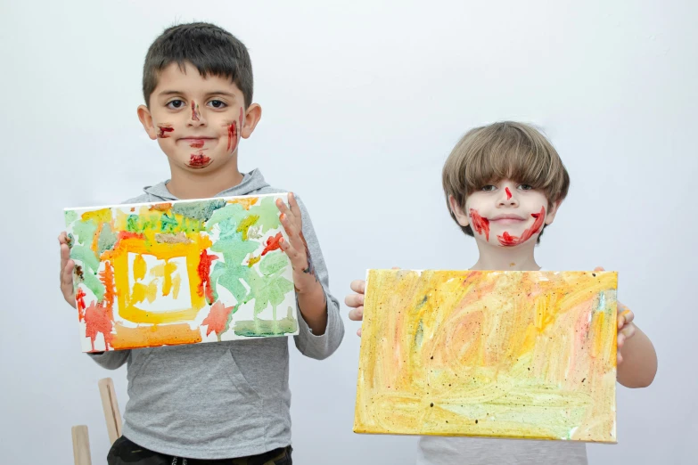 two young children with face painted hold art