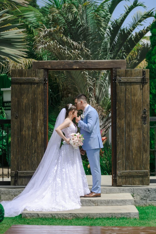 a bride and groom posing in front of an outdoor area with palm trees