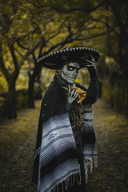 a man dressed as a skeleton wearing an elaborate hat, scarf, and cape