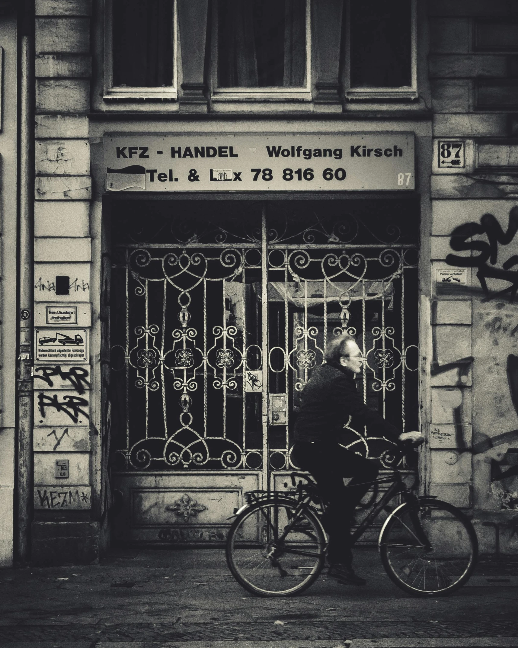 old man standing outside building with his bike in front