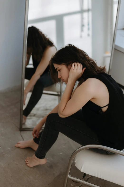 a woman sitting on a chair in front of a mirror