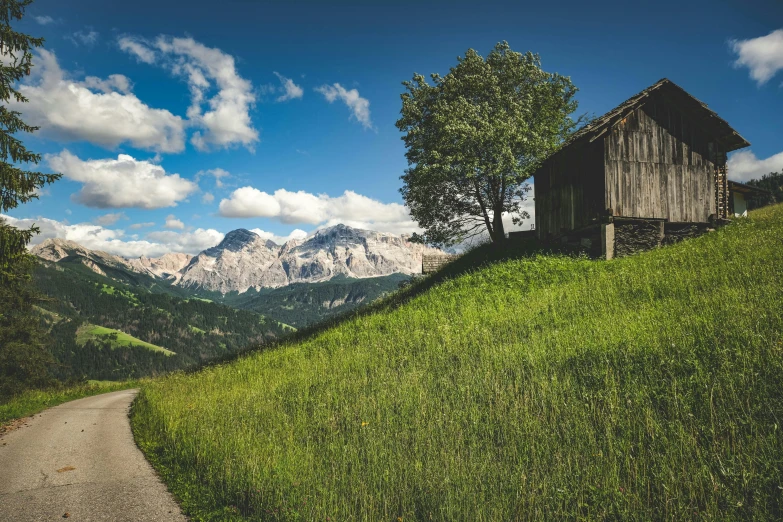 the grassy hills are lush with trees and a little hut next to it