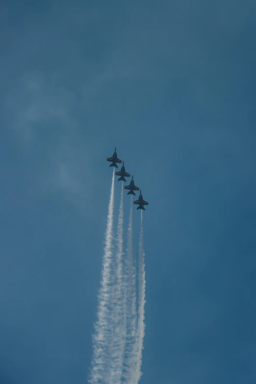 four fighter jets flying in formation with smoke trails