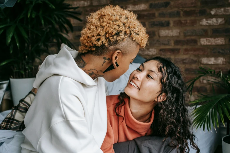 two girls playing and laughing next to a brick wall