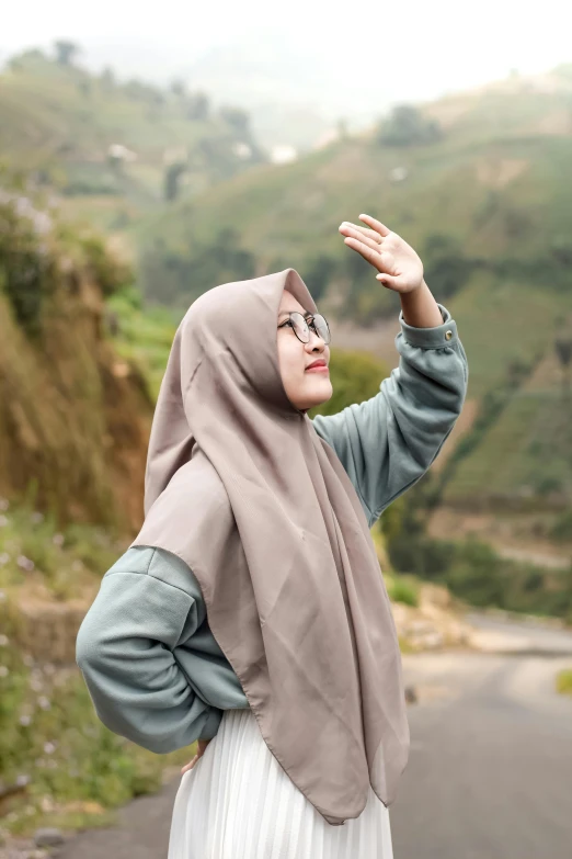 a young woman in a hijab on a hill top