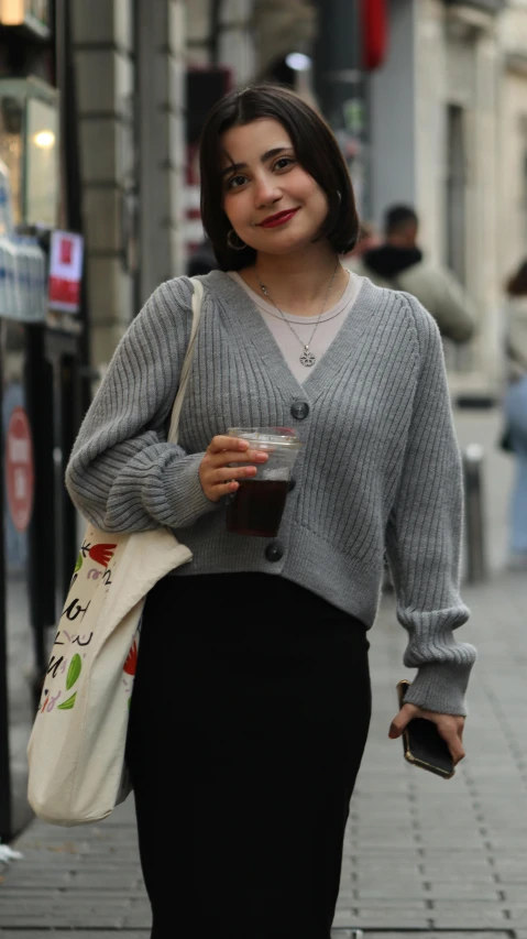 a woman standing on the sidewalk with a cup