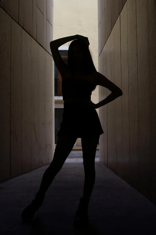 a dark silhouette of a woman leaning against a wall