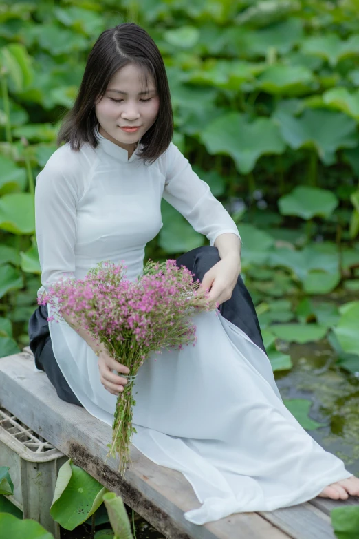 a woman sitting on a bench next to some flowers