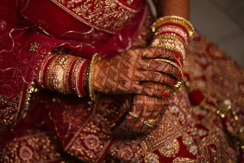 the bridal hands are showing the gold and red jewelry