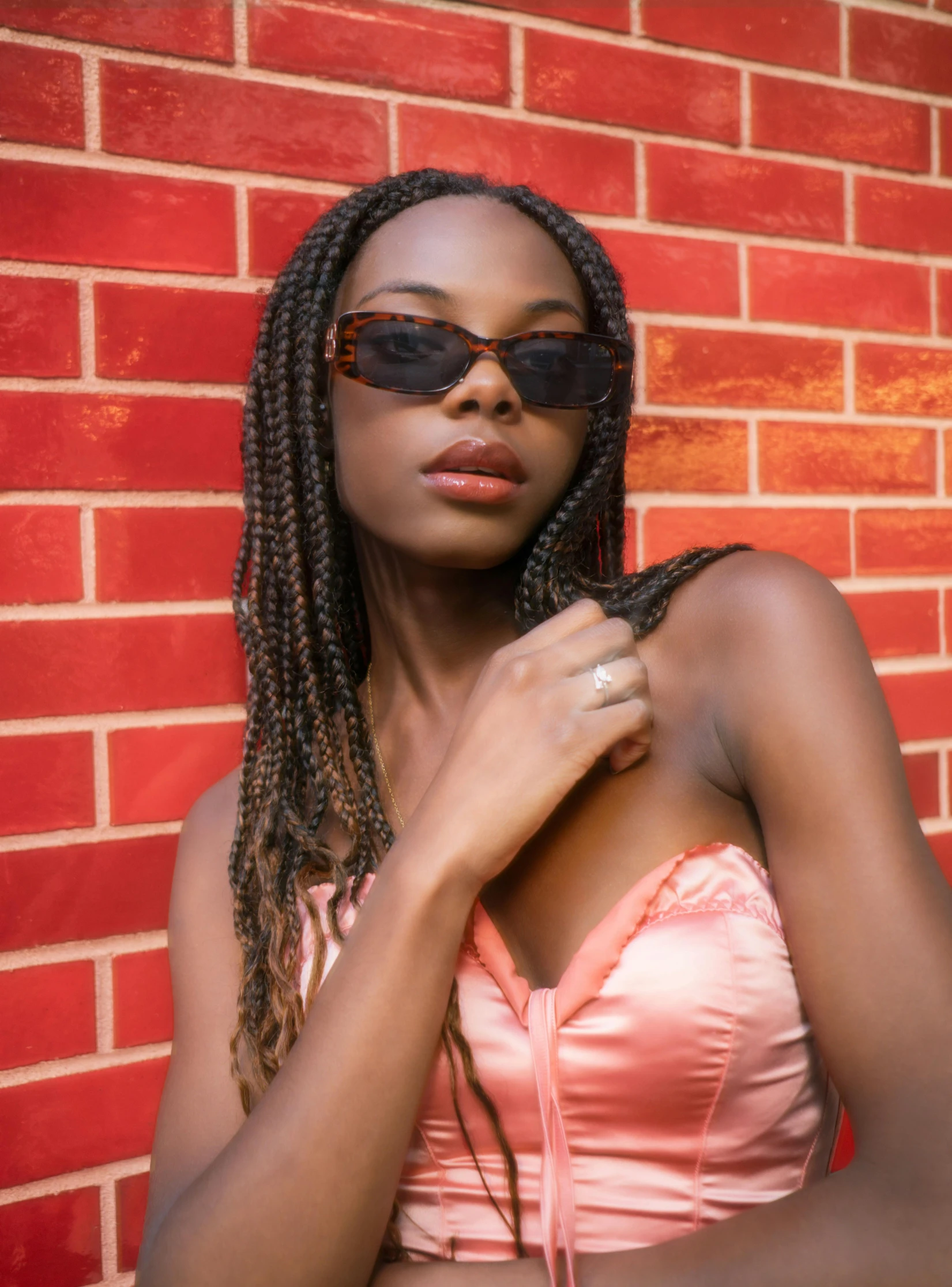 an attractive young woman posing against a brick wall