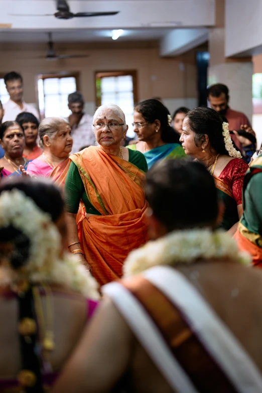 an older woman standing in front of a crowd of people