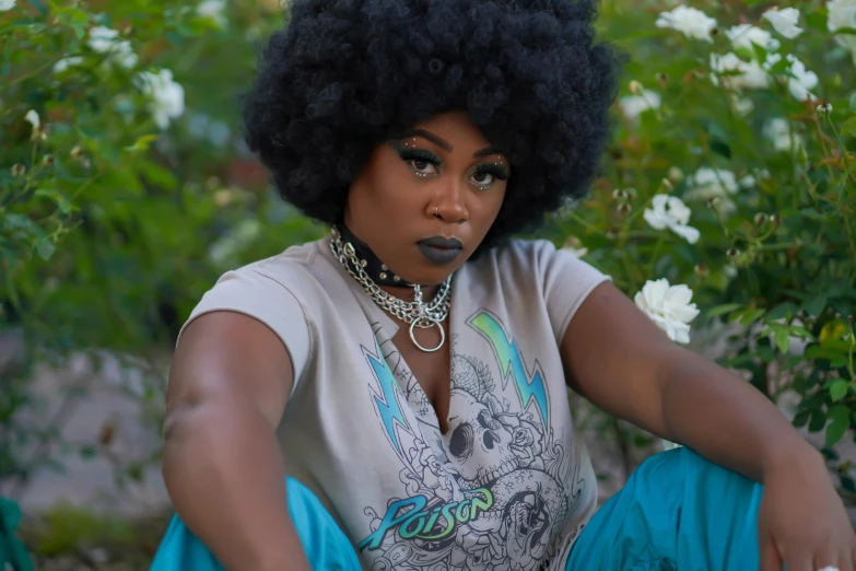 a woman with afro hair sitting in front of flowers