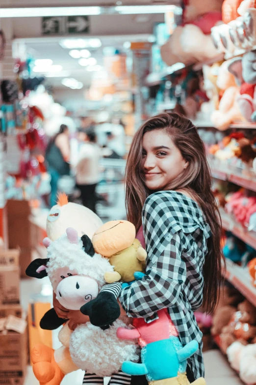 a woman holding a teddy bear and stuffed cow plush animal in a store