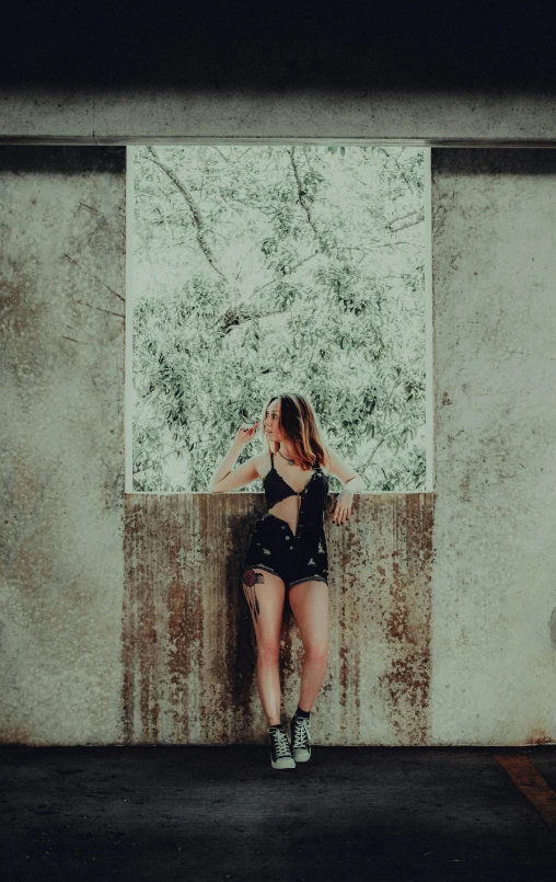 a young woman in a  top leaning against a concrete wall