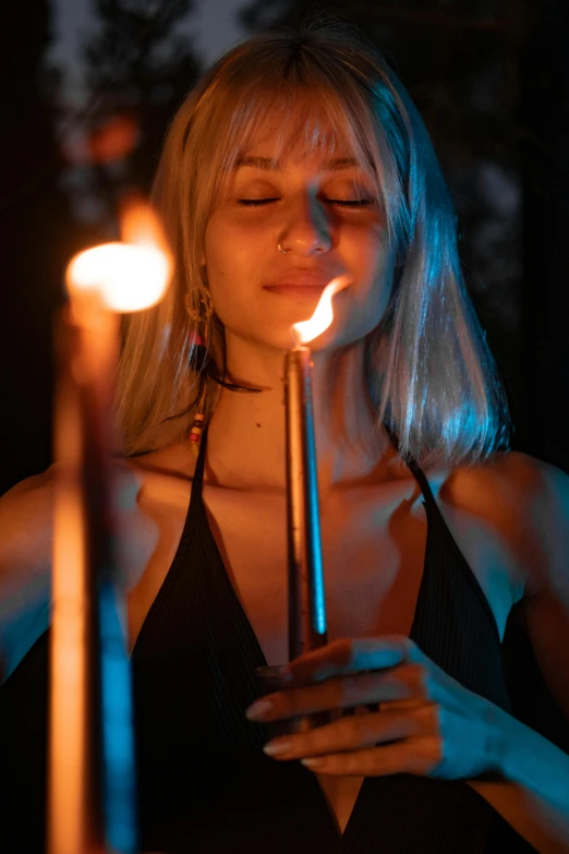 woman holding candle sticks lite up at night