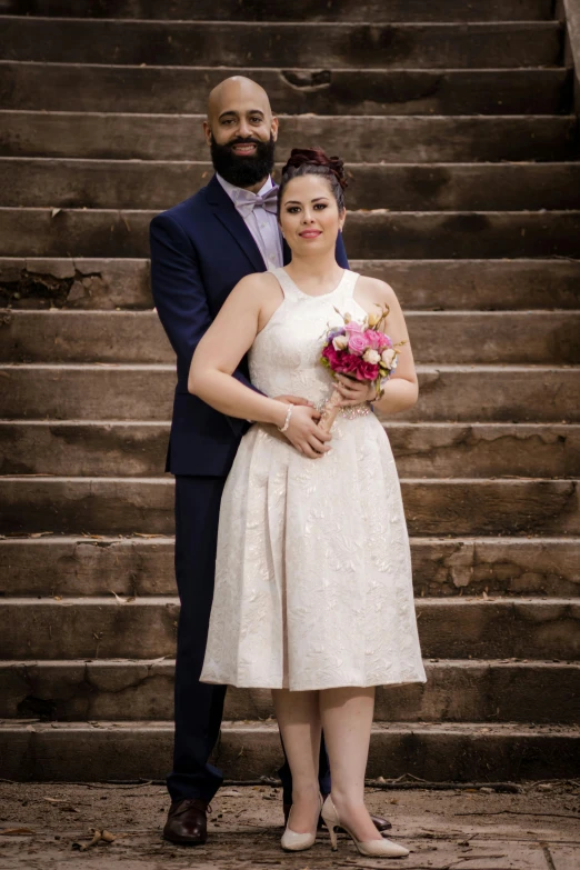 a couple poses for a picture with flowers on their bouquet