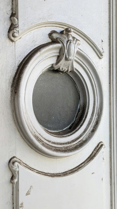 a white door has a large circular window above the door handle