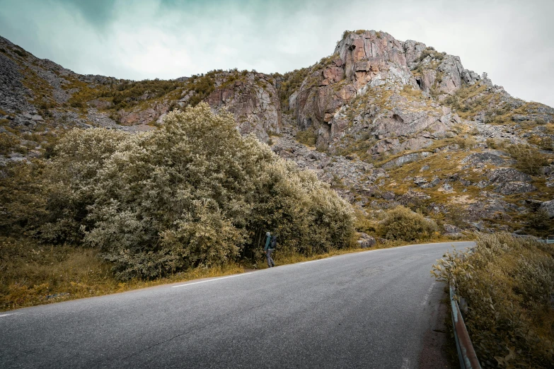 a scenic landscape in the mountains with a curveed road and a bench