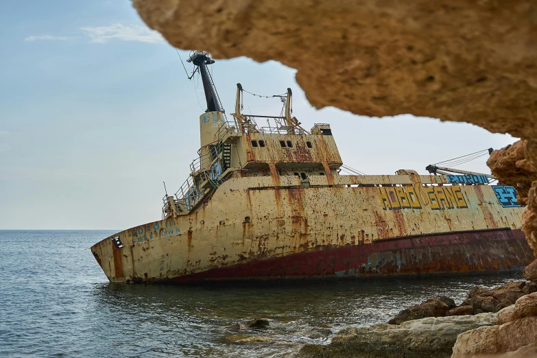 a rusty, rusted boat sits in a large body of water near the shore