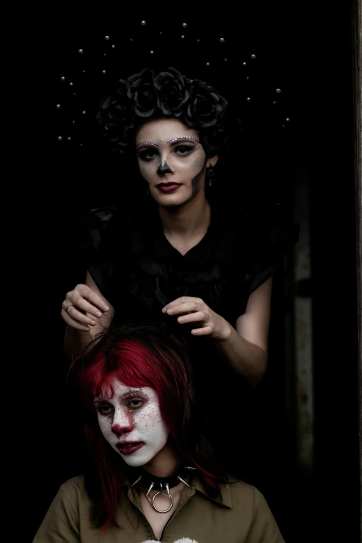 two women with dark makeup and make - up with fake hair, one of them has her hair combed